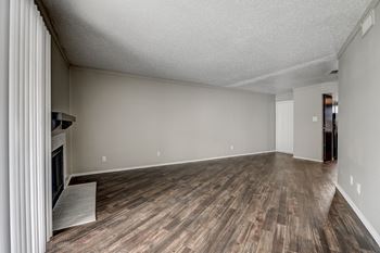 A room with wooden flooring and a fireplace on the left side.